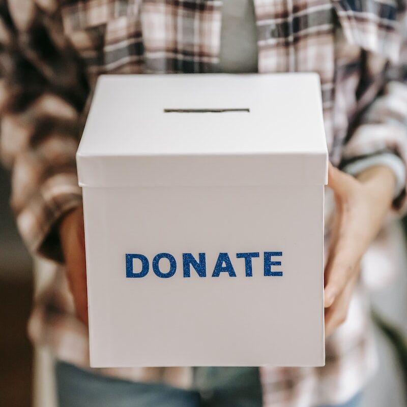 Crop anonymous person showing donation box