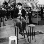 16 kwietnia - Charlie Chaplin - grayscale photo of man in black jacket sitting on chair